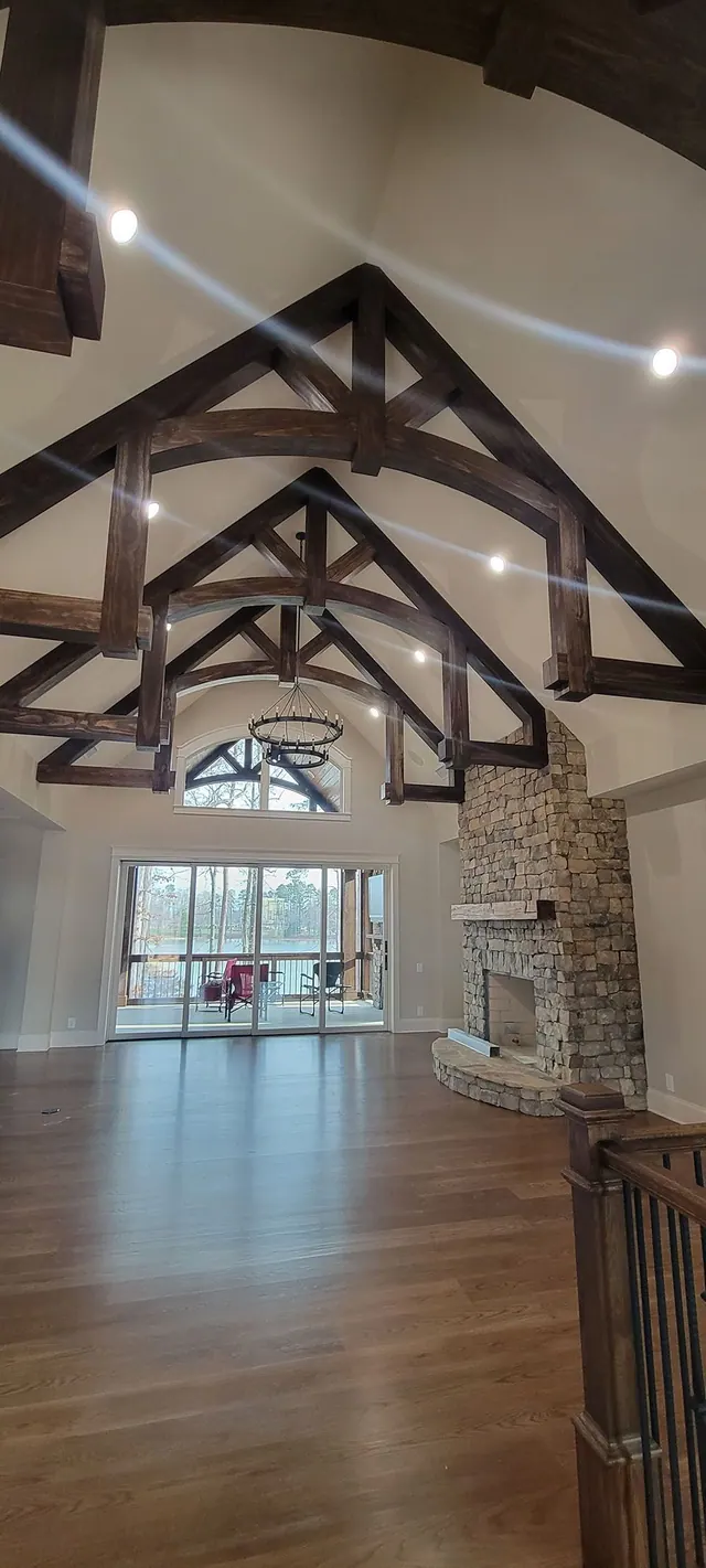 A great room with vaulted wood beam ceilings and a stacked-stone fireplace.