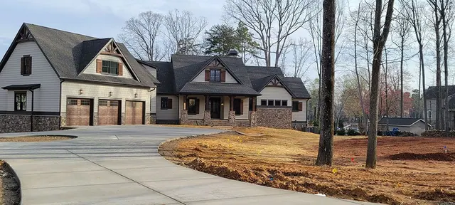 A newly built house with a stone-accented exterior and a freshly poured concrete driveway.