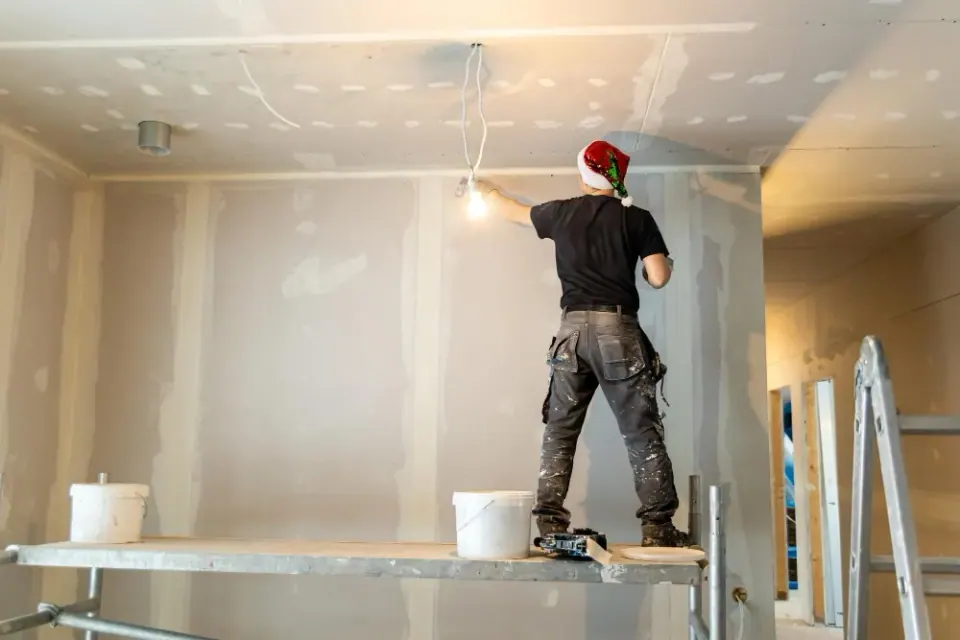 Finisher on a scaffold plank smoothing seams on a freshly hung ceiling.