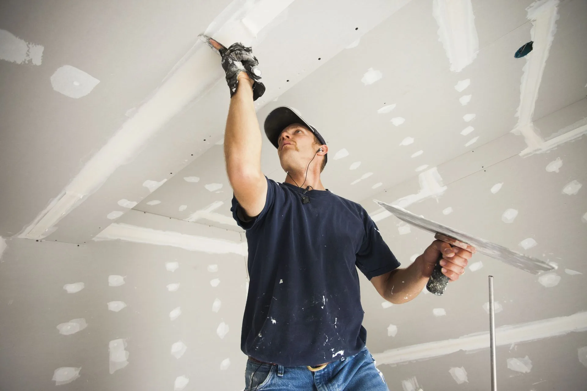 Drywall finisher smoothing joint compound along a ceiling seam during a Conover, NC drywall job.